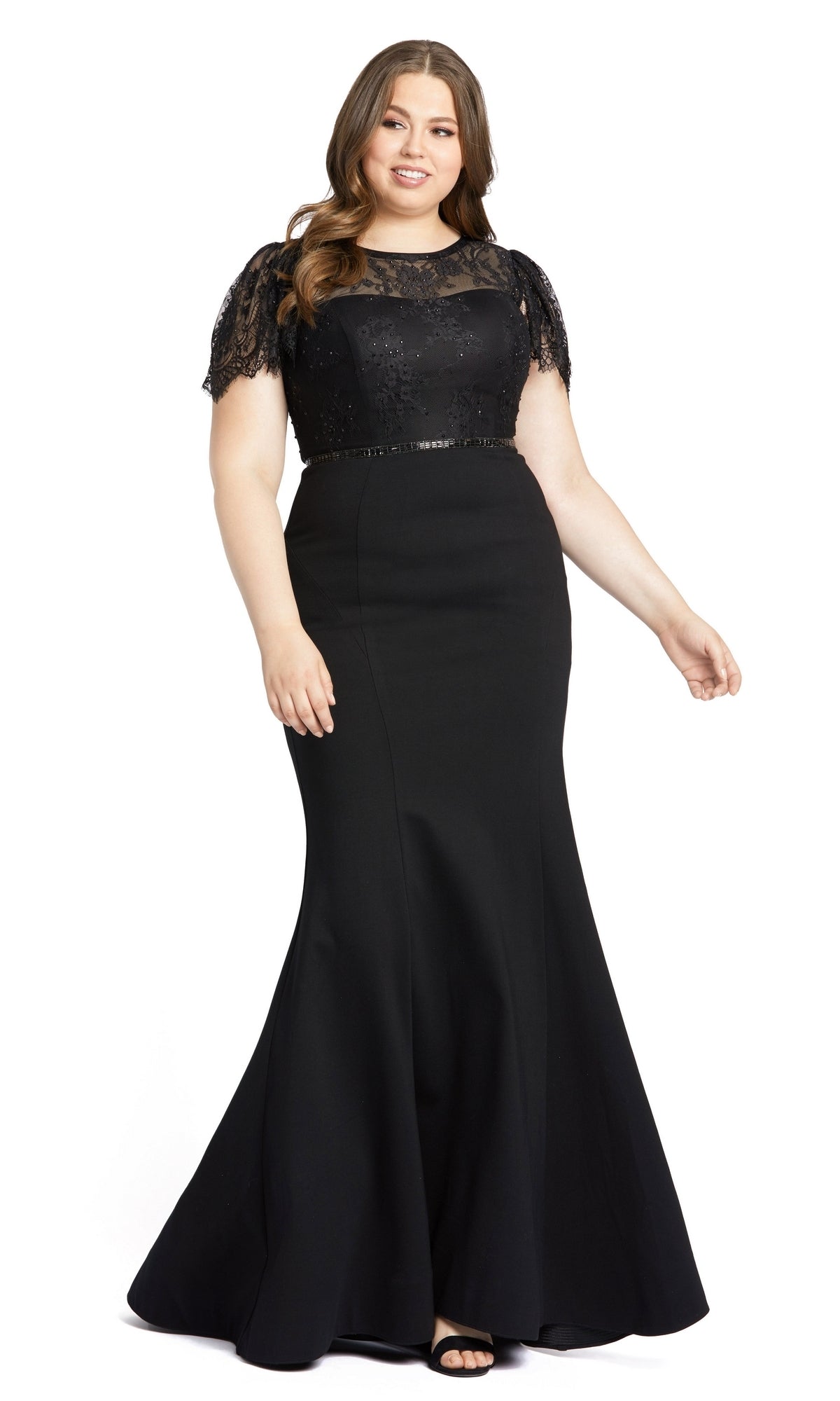 A woman wearing the Long Plus-Size Formal Dress 48984 by Mac Duggal, a floor-length black mermaid gown with lace flutter sleeves and a fitted bodice, stands against a white background.